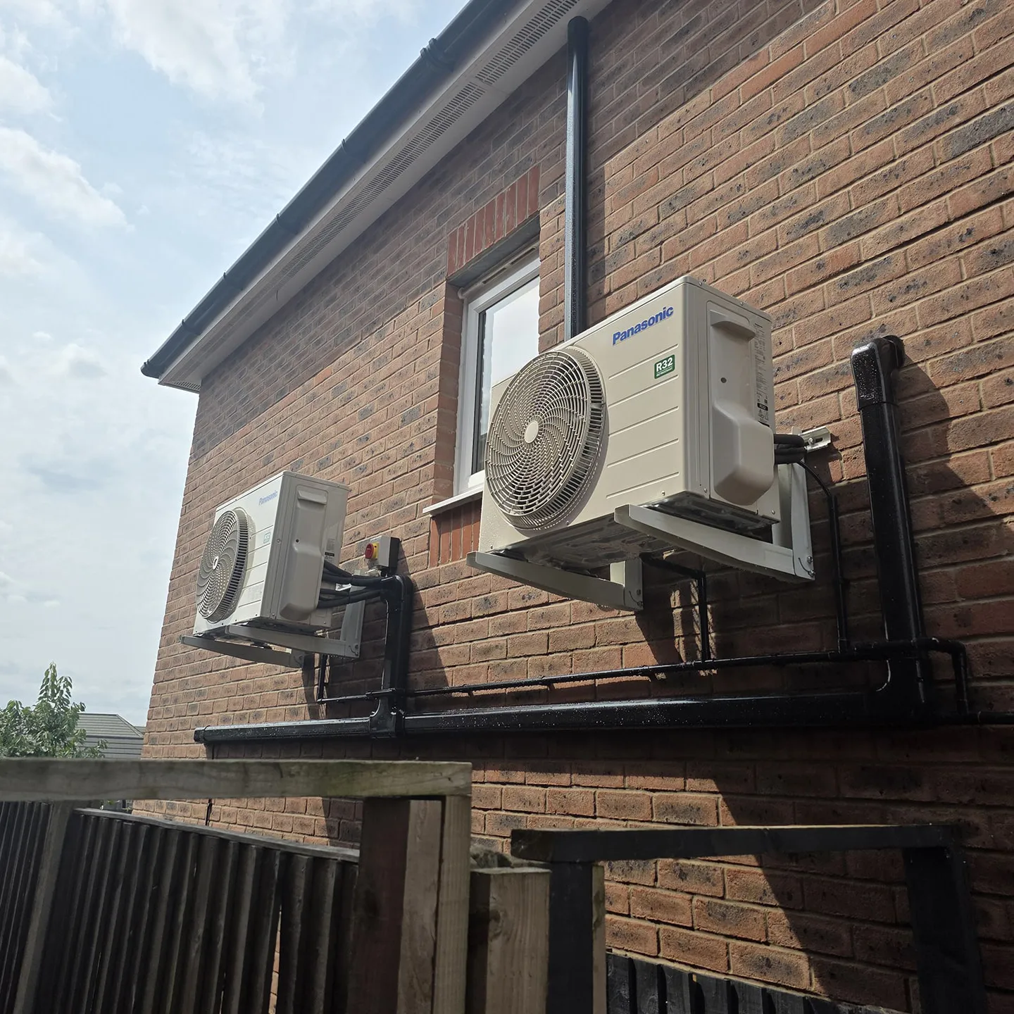 Three Panasonic air conditioning outdoor units on wall brackets