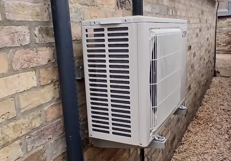Air conditioning outdoor unit wall-mounted in a side passage