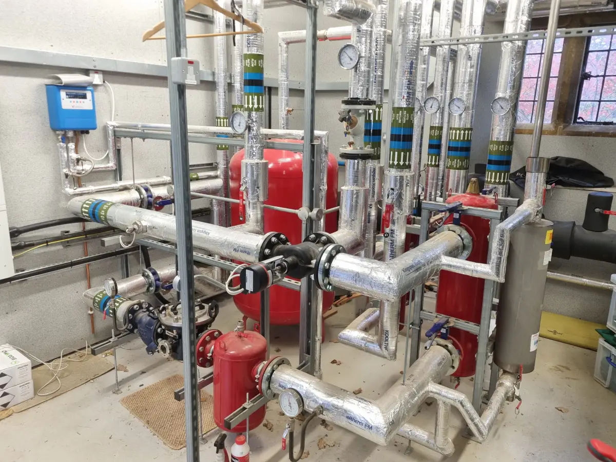 Commercial plant room with red expansion vessels and insulated pipework